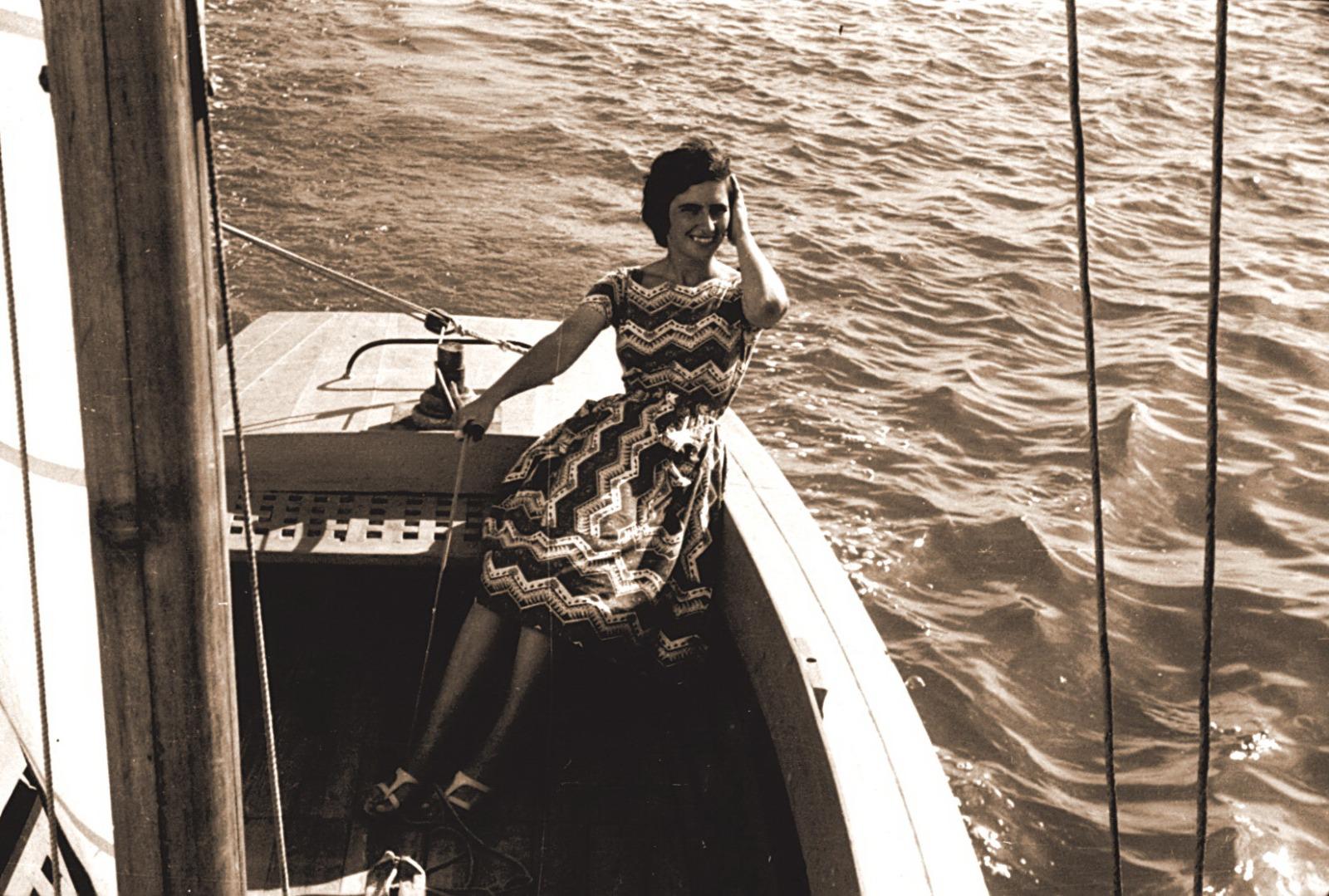 Fotografia antiga da avó Marília sentada a bordo de um veleiro, a sorrir, com a água ao lado